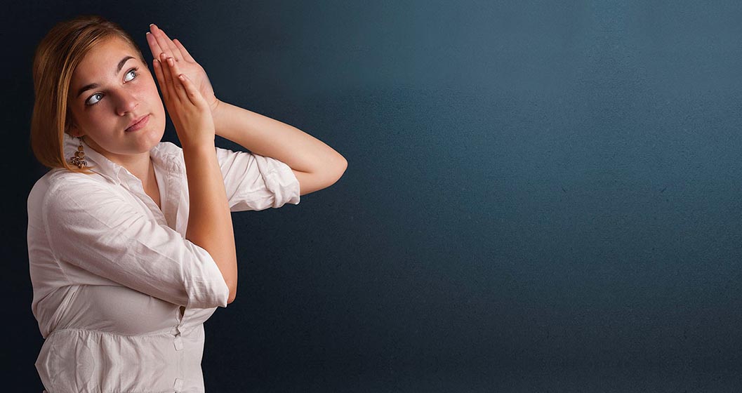 Young woman holds her hands up to her ear to hear what's happening