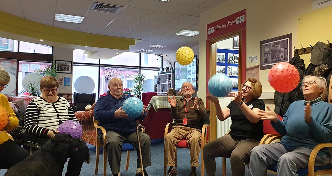 Seated adults doing exercises with balls