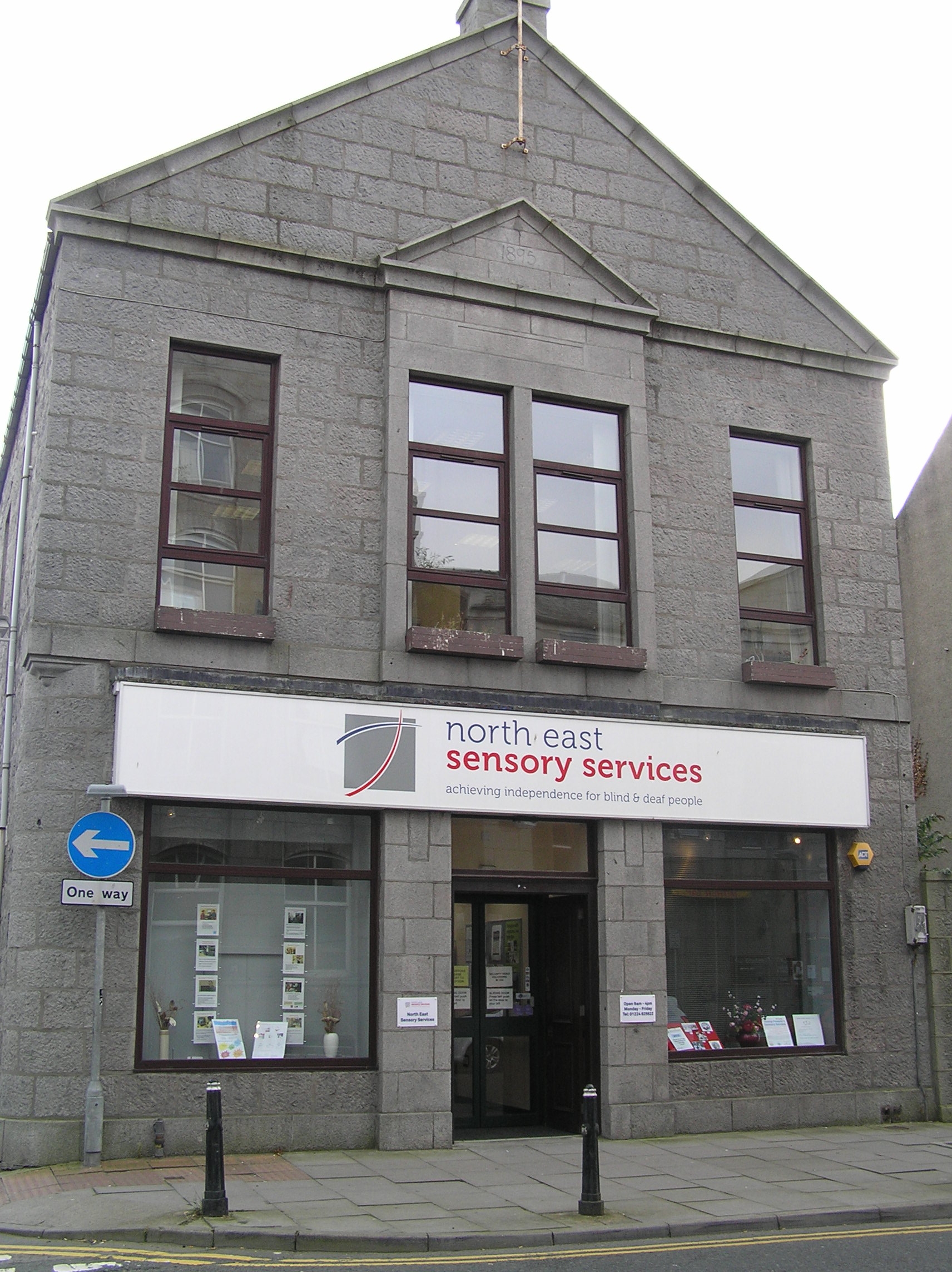 Front elevation of NESS Resource Centre on John Street, in Aberdeen. Large building, with large windows, and NESS sign over the door