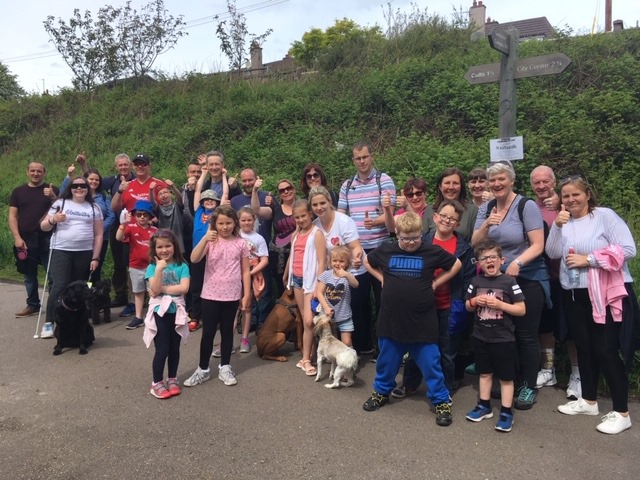 Group of young people and their families standing together oustide in a park 