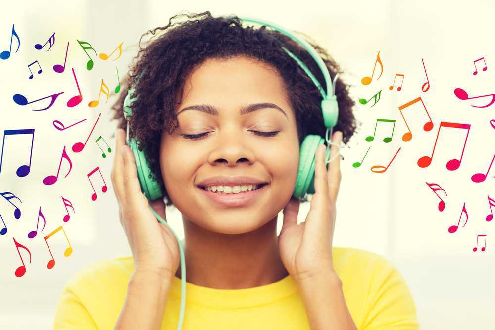 Young woman enjoying listening to musici with multi coloured musical notes surrounding her