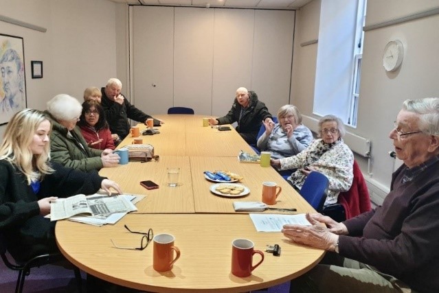 Dundee group member John Black delivering a talk on the Stone of Destiny to a small group sitting round a table