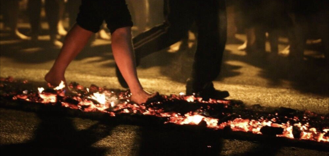 image of people walking across burning embers in the dark