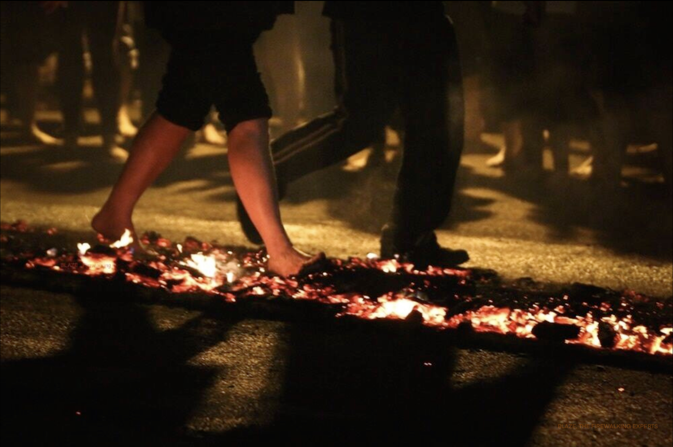 image of people walking across burning embers in the dark