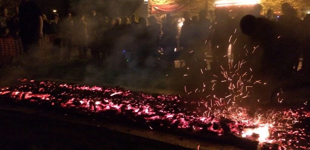 crowd of people looking on at the burning embers of a firewalk