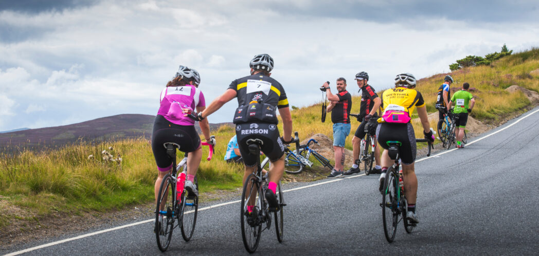 image of cyclists riding along a road, wearing colour cycle gear