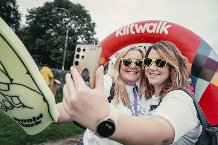 two ladies wearing sunglasses taking a 'selfie' at the Kiltwalk starting line